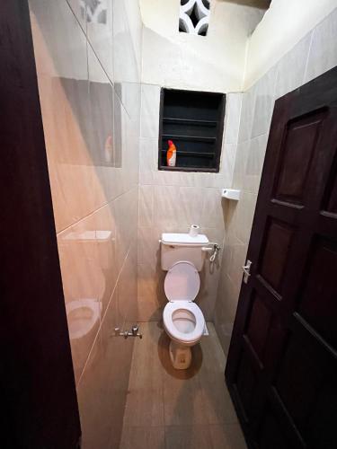 a bathroom with a toilet and a window and a door at Kijijini GuestHouse Gazi in Gazi