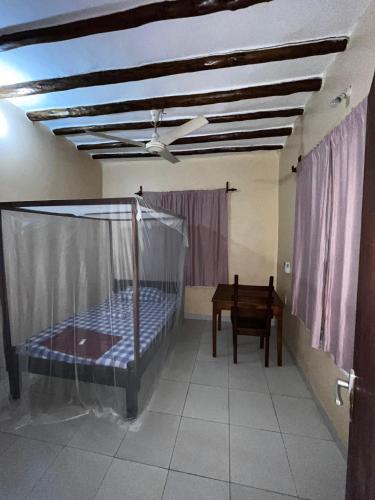 a bedroom with a bed and a table and a ceiling at Kijijini GuestHouse Gazi in Gazi
