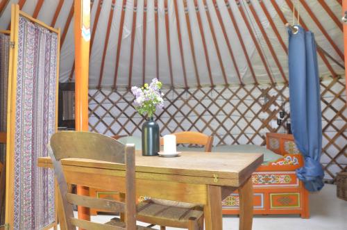 a wooden table with flowers in a yurt at Le portillon des fées in Sost