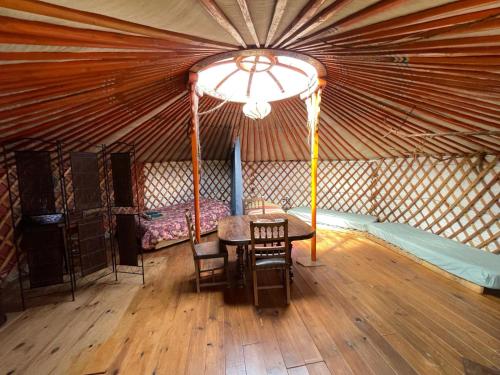 a room with a table and chairs in a yurt at Le portillon des fées in Sost
