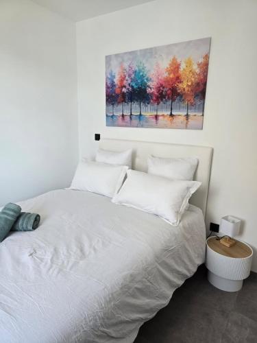 a bedroom with a white bed with a painting on the wall at Skyline Rooftop Swim Spa in Montpellier