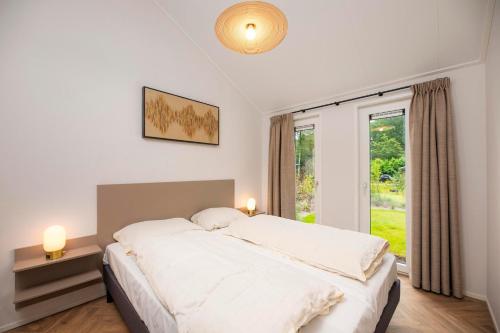 a bedroom with a large white bed and a window at Veluwepark de Bosgraaf in Apeldoorn
