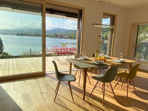 a dining room with a table and chairs and a view at Villa Über-See with private beach in Pörtschach am Wörthersee