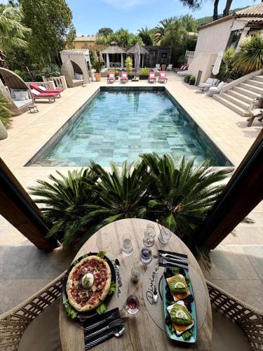 a table with food on it next to a swimming pool at La Villa Dune, Hôtel & Spa in Saint-Tropez