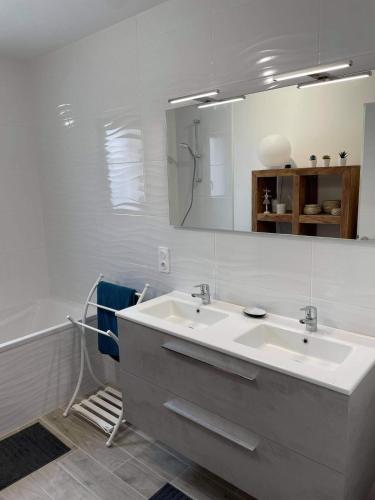 une salle de bain blanche avec un lavabo et un miroir dans l'établissement Maison familiale en bord de mer avec JACUZZI, à Vaux-sur-Mer
