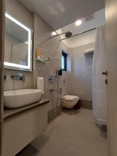 a bathroom with a sink and a toilet and a mirror at Hotel 24K Nagpur in Nagpur