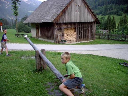 a young boy sitting on a fence in front of a barn at Govc-Vršnik in Solčava