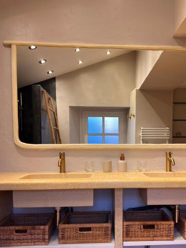 une salle de bain avec un lavabo et un grand miroir dans l'établissement Le Moulin de Montségur, à Montségur-sur-Lauzon