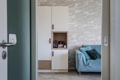 a living room with a blue couch and a cabinet at Paal 8 Hotel aan Zee in West aan Zee