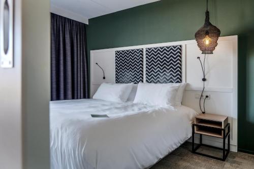 a bedroom with a white bed and a green wall at Paal 8 Hotel aan Zee in West aan Zee