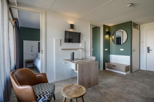 a room with a chair a desk and a mirror at Paal 8 Hotel aan Zee in West aan Zee