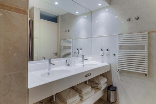 a white bathroom with a sink and a mirror at Paal 8 Hotel aan Zee in West aan Zee