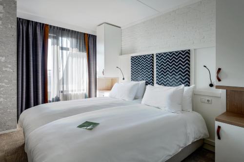 a large white bed in a room with a window at Paal 8 Hotel aan Zee in West aan Zee