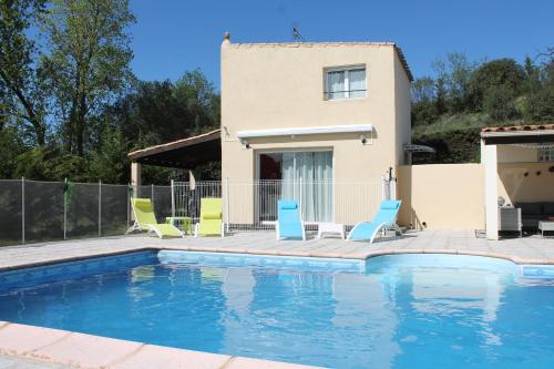 une piscine avec des chaises et une maison en arrière-plan dans l'établissement Gîte Les Amandiers, à Villedubert