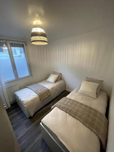 une chambre avec deux lits et un lustre dans l'établissement 1 apartement en centre ville, à Nogent-sur-Oise