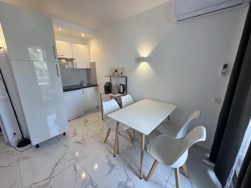 une petite cuisine avec une table et des chaises blanches dans l'établissement Résidence Graziella Studio 504, à Juan-les-Pins