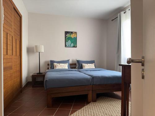 a bedroom with a bed with blue sheets and a window at Harmony Villa - Port Chambly in Mauritius