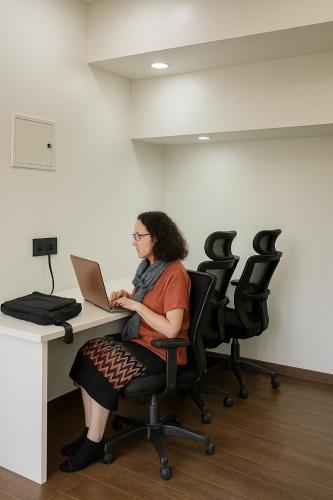 a woman sitting at a desk with a laptop at The Metrostay Opposite New Delhi Railway Station, Above Metro, 20 Mins From IGI Airport in New Delhi