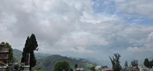 a cloudy sky over a city with a mountain at Holiday hills homestay in Bomdila