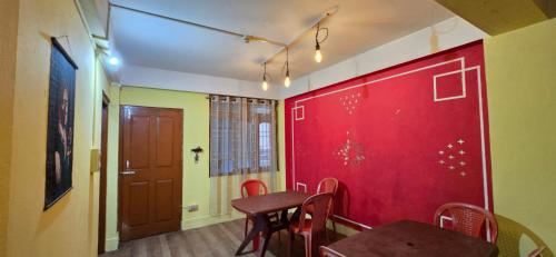 a room with a table and chairs and a red wall at Holiday hills homestay in Bomdila
