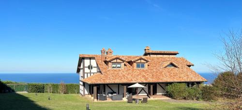 a large house with a red roof on a hill at Magnífica villa mirando al mar in Suances
