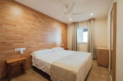 a bedroom with a bed and a wooden wall at Apartamentos Blancala in Cala Blanca