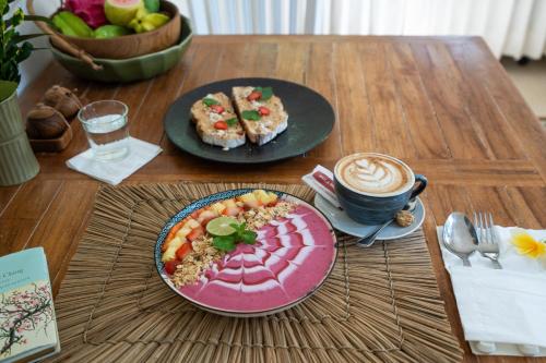 une table avec deux assiettes de nourriture et une tasse de café dans l'établissement Moon & Honey villa, à Ubud