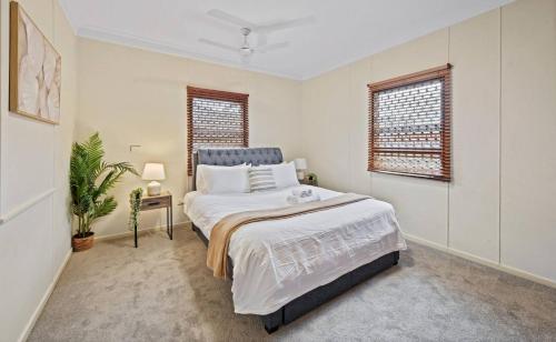 ein Schlafzimmer mit einem großen Bett und zwei Fenstern in der Unterkunft Cozy Queen Room Walk To Museum & Marketplace - Bedroom4 in Yatala