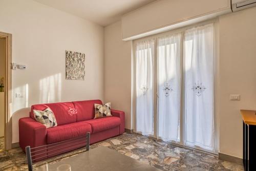 a living room with a red couch and a large window at Loano Mare in Loano