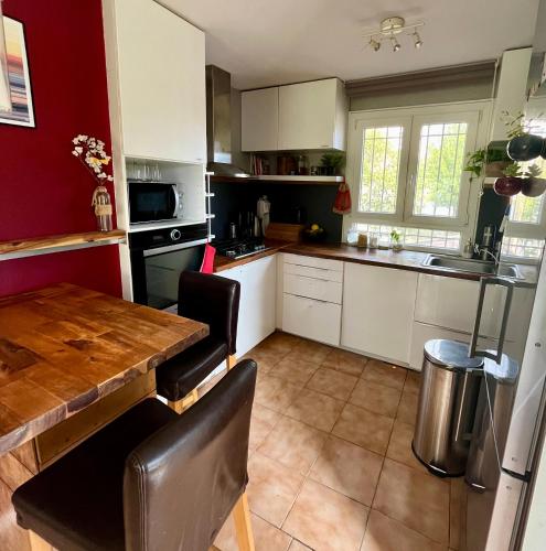 a kitchen with a wooden table and white cabinets at Le dindouleto in Peynier