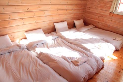 two white beds in a room with wooden walls at 彩の宿虹 in Yamanakako