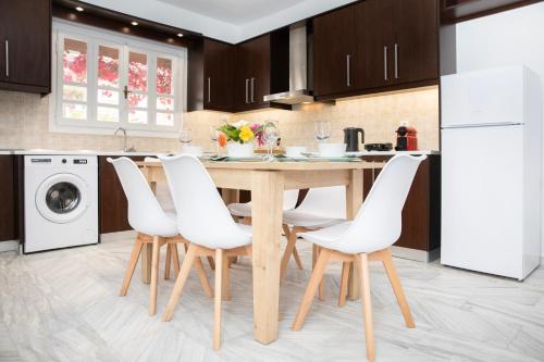 eine Küche mit einem Holztisch und weißen Stühlen in der Unterkunft ChrisAri House in Zipárion