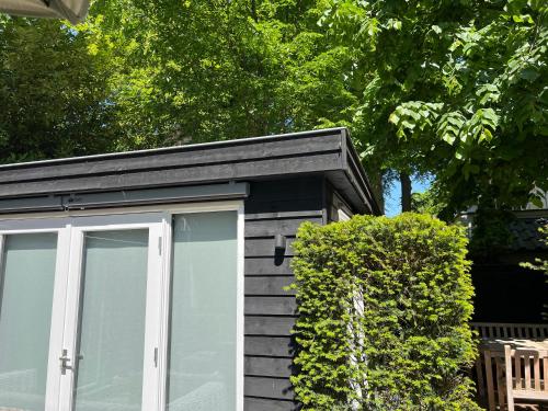 a small shed with a white door next to a bush at de Merel in Vught