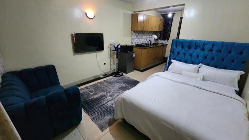 a bedroom with a large bed and a blue chair at DNG Homes Cute studio apartment Polyview, Kisumu in Kisumu