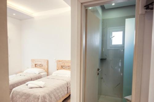 a bedroom with two beds and a door to a bathroom at Cyclades Hotel in Karterados