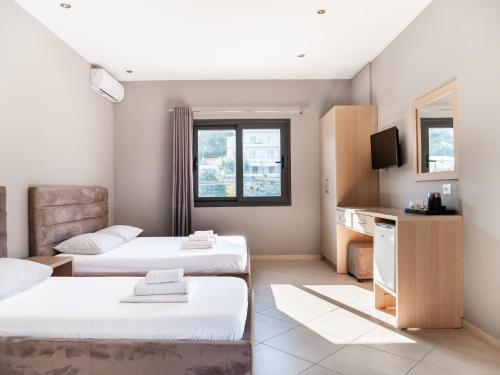 a room with two beds and a tv at Endless Blue Himara in Himare