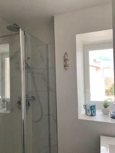 une salle de bain avec une douche avec une porte vitrée dans l'établissement Villa Louise à 500 m des plages, à Royan