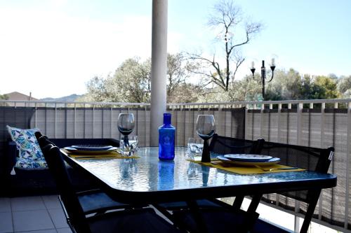 une table avec des verres à vin et une bouteille bleue sur un balcon dans l'établissement Studio Terrasse entre ville et port, à Porto-Vecchio