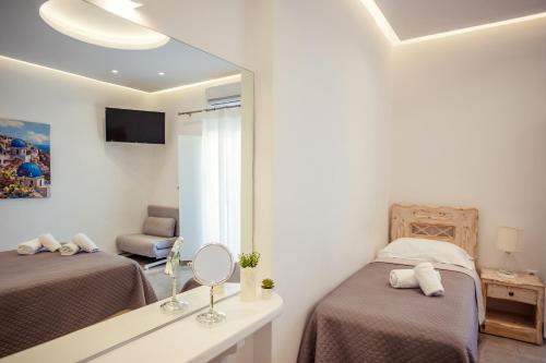 a white room with two beds and a mirror at Cyclades Hotel in Karterados