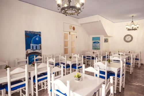 a dining room with white tables and white chairs at Cyclades Hotel in Karterados