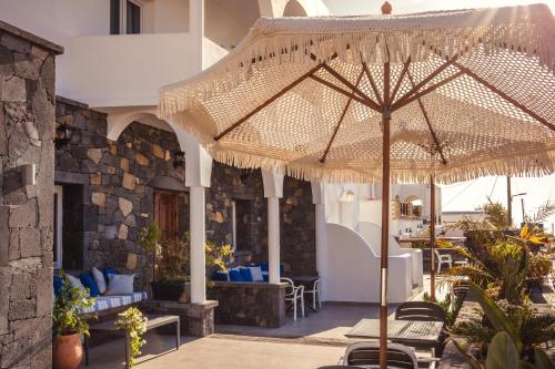 an umbrella on a patio with chairs and tables at Cyclades Hotel in Karterados