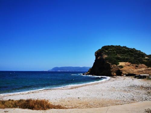 a beach with the ocean and a cliff at Traditional stone guesthouse in Agios Andreas