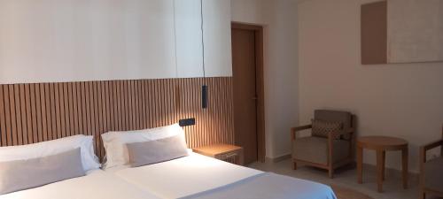 a bedroom with a white bed and a chair at Hotel Bahia Pollensa in Port de Pollensa
