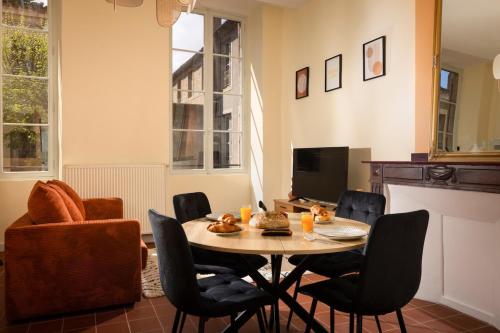 un salon avec une table avec des chaises et une télévision dans l'établissement L'instant Voltaire, à Carcassonne
