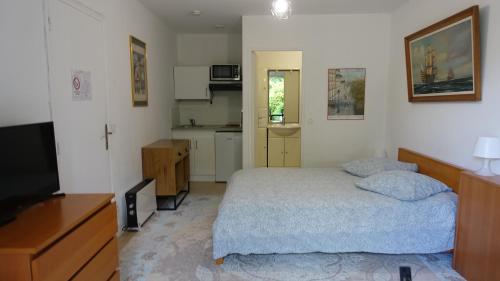 a small bedroom with a bed and a kitchen at Coeuilly village parisien Champigny sur Marne in Champigny-sur-Marne