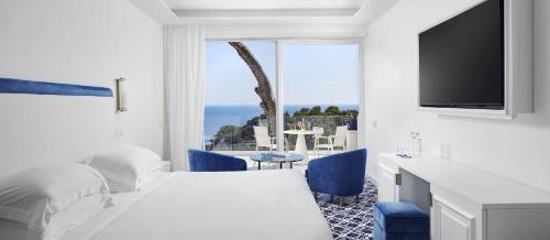 a hotel room with a bed and a tv and a table at Hotel Scalinatella in Capri