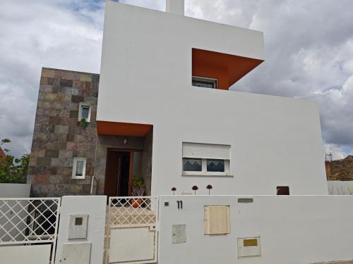 a white house with a fence in front of it at Quarto privado Alentejo Litoral in Grândola