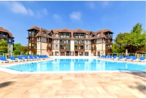 une grande piscine avec des chaises bleues en face d'un bâtiment dans l'établissement birdie-deauville, à Deauville