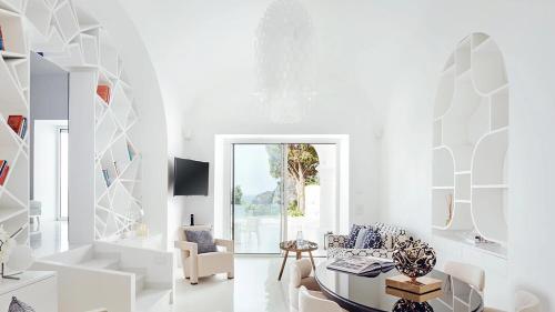 a white living room with a table and chairs at Hotel Scalinatella in Capri