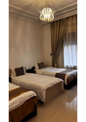 a bedroom with two beds and a chandelier at abha condo in Abha